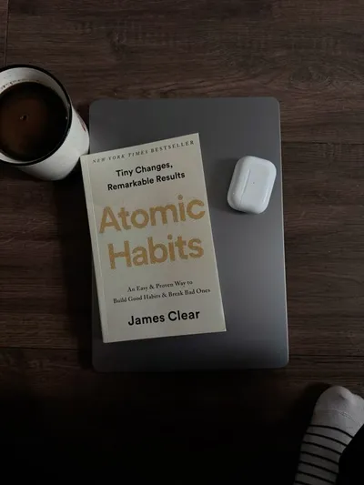 The book Atomic Habits on a laptop next to a coffee