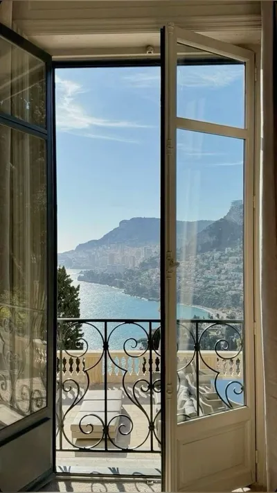 Open balcony doors with a view of a coastal town